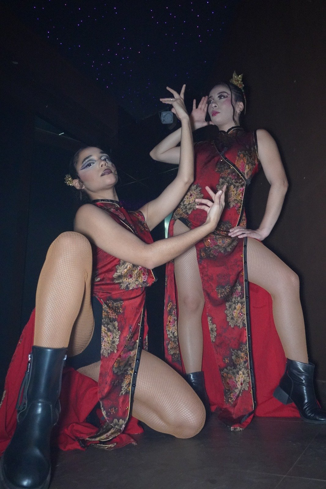 Two dancers in red qipao dresses in a sculpted pose